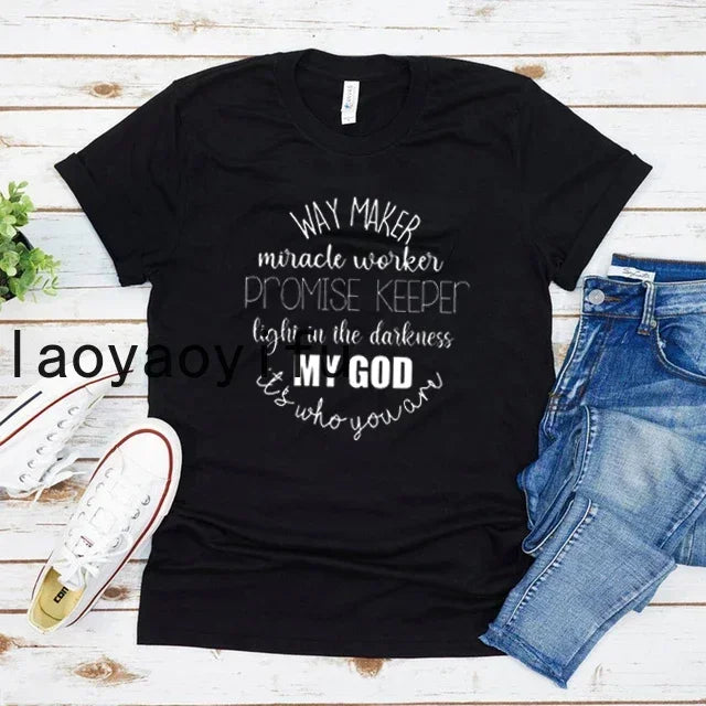 Black t-shirt with text design on a wooden surface with jeans and shoes.